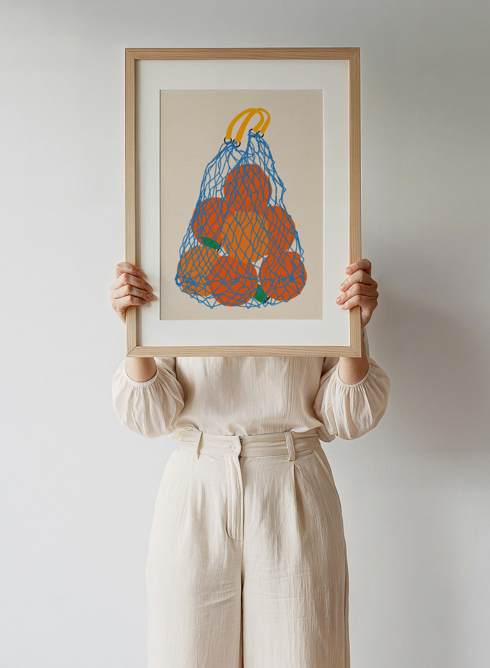 Blue mesh bag filled with orange fruits on a beige background. Oranges In a Net Bag by Rosi Feist is a modern minimalist fruit art print with bold color and Bauhaus-inspired graphic design. Officially licensed fine art poster with framing.