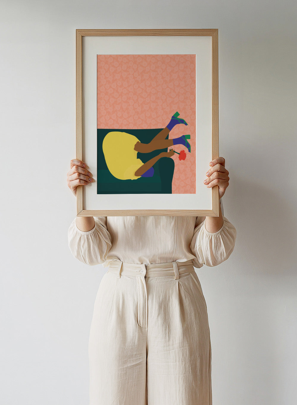 Illustration of a person sitting on a couch with a flower, against a patterned pink background. New Year’s Eve by Jota De Jai is a playful modern fine art print of a woman upside down on a couch in heels and a yellow dress. Available framed or unframed.