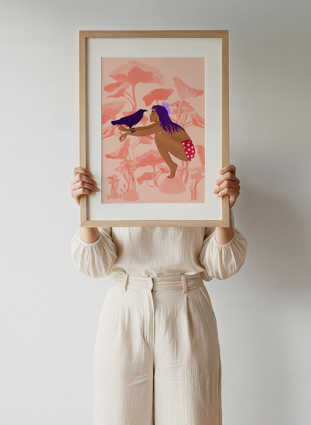 Illustration of a woman with a bird on a pink floral background. Raven by Jota de Jai is a modern pink wall art print of a woman with a purple raven, available as a premium fine art poster with optional wood framing.