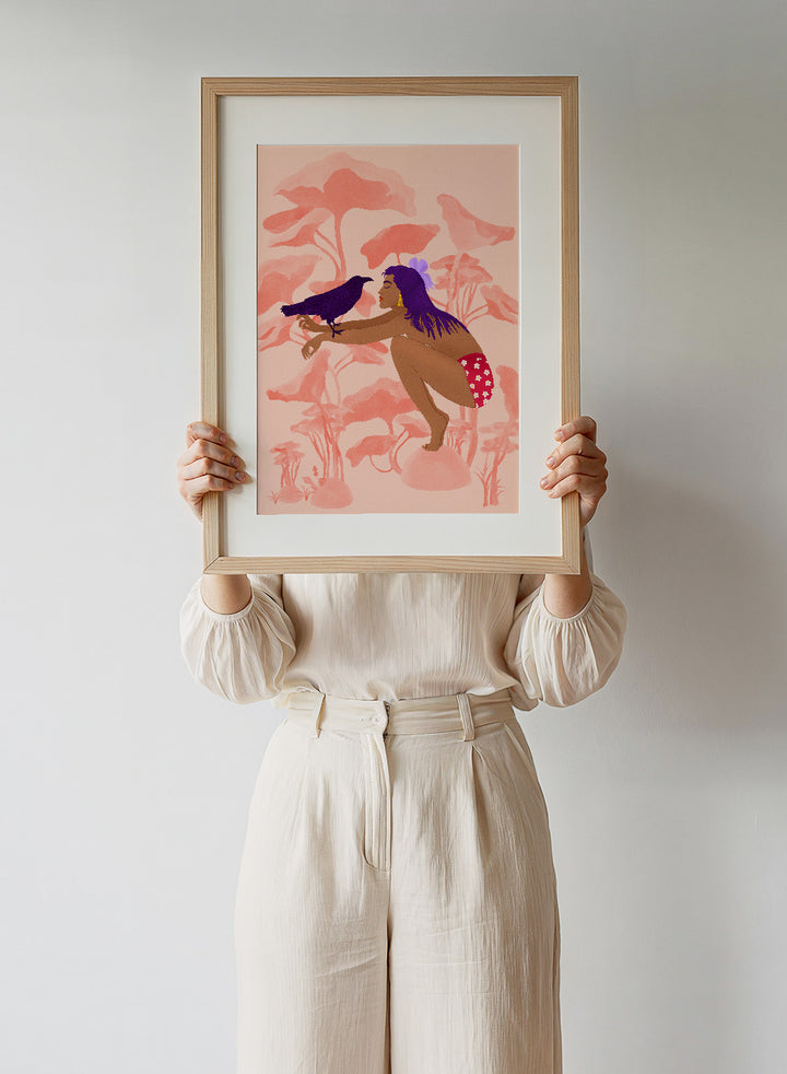 Illustration of a woman with a bird on a pink floral background. Raven by Jota de Jai is a modern pink wall art print of a woman with a purple raven, available as a premium fine art poster with optional wood framing.