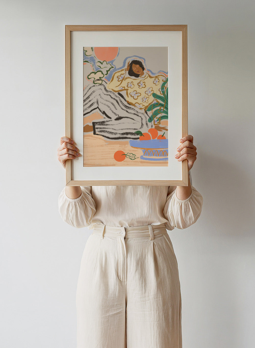 Artistic depiction of a person lounging on a beach with a bowl of fruit and flowers. Lazy Days by Arty Guava is a modern woman art print with warm colors, oranges, and relaxed still life details. Officially licensed wall poster.