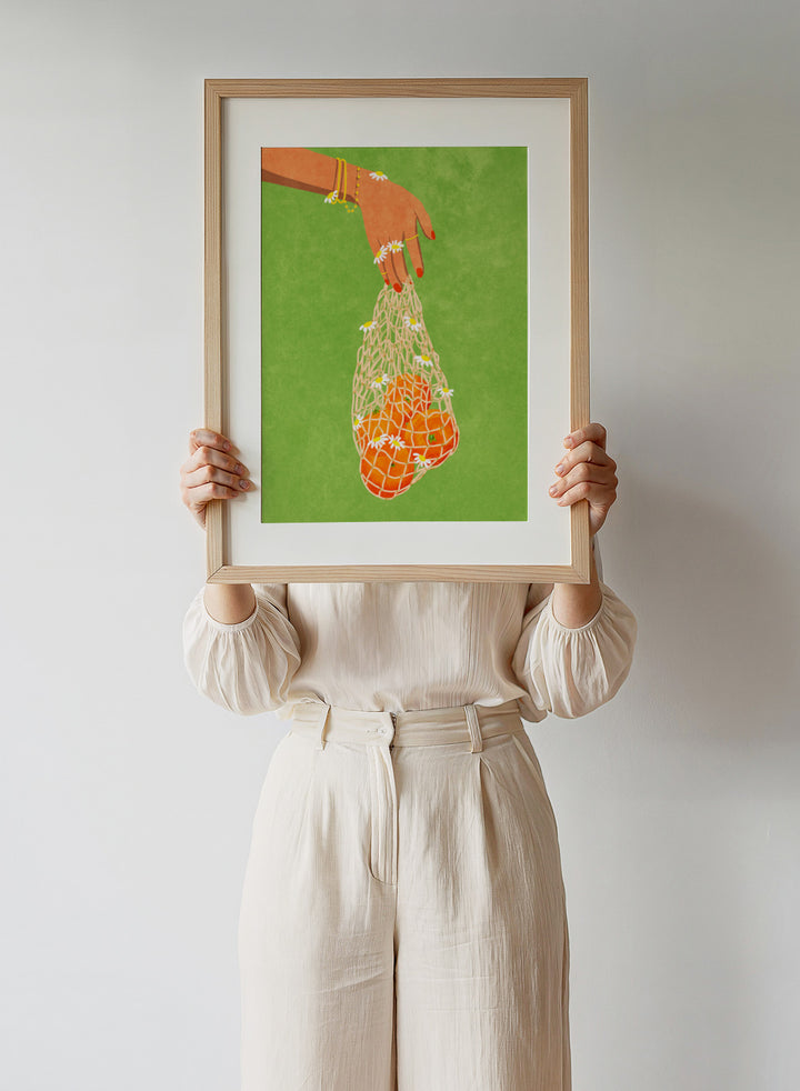 Illustration of a hand holding a bag of oranges with a green background. Fresh Oranges by Raissa Oltmanns fine art print featuring modern fruit illustration, stylish feminine hand art, contemporary kitchen wall decor poster.