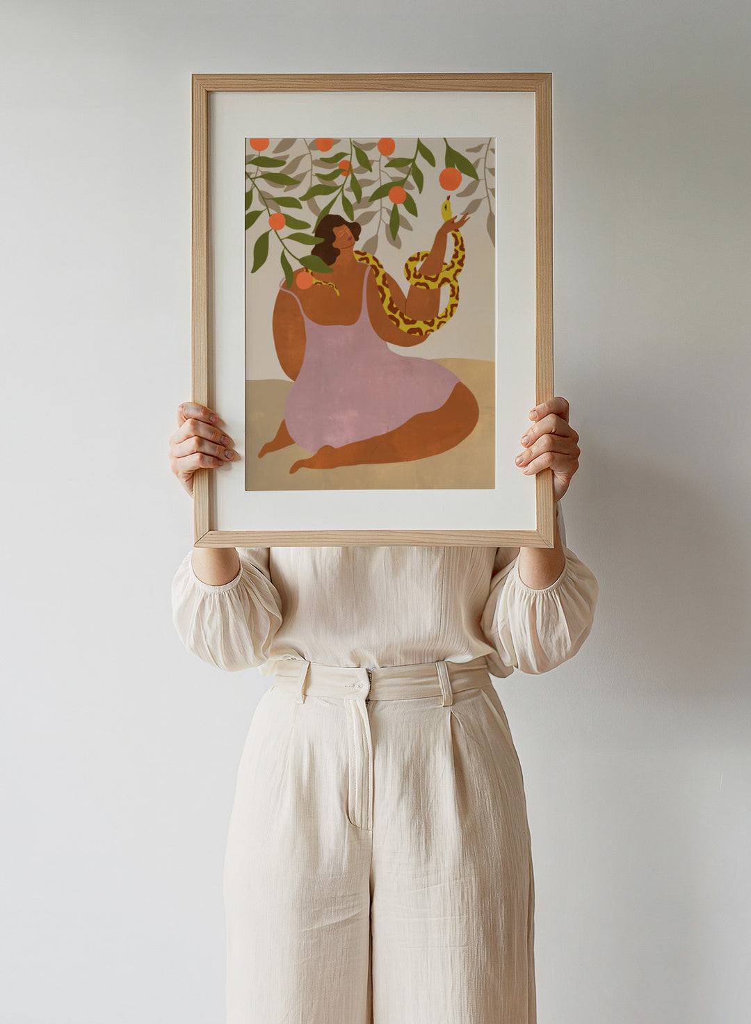 Illustration of a woman holding a snake with oranges and leaves in the background. Eden’s Embrace by Arty Guava art print featuring woman with snake under orange tree branches, tropical nature illustration, and vibrant contemporary wall art poster.