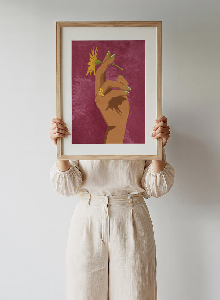 Illustration of a hand holding a yellow flower against a pink background. Smoking Flower by Raissa Oltmanns is a modern floral art print featuring a hand holding a yellow flower in bold contemporary wall poster style.