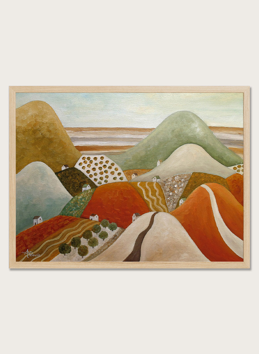 A framed landscape painting featuring stylized rolling hills and fields in earthy tones of orange, green, beige, and brown. Shop Colorful Hillside Village by Angeles M. Pomata, an autumn landscape art print featuring rolling hills, tiny homes, winding roads, and warm earthy tones.
