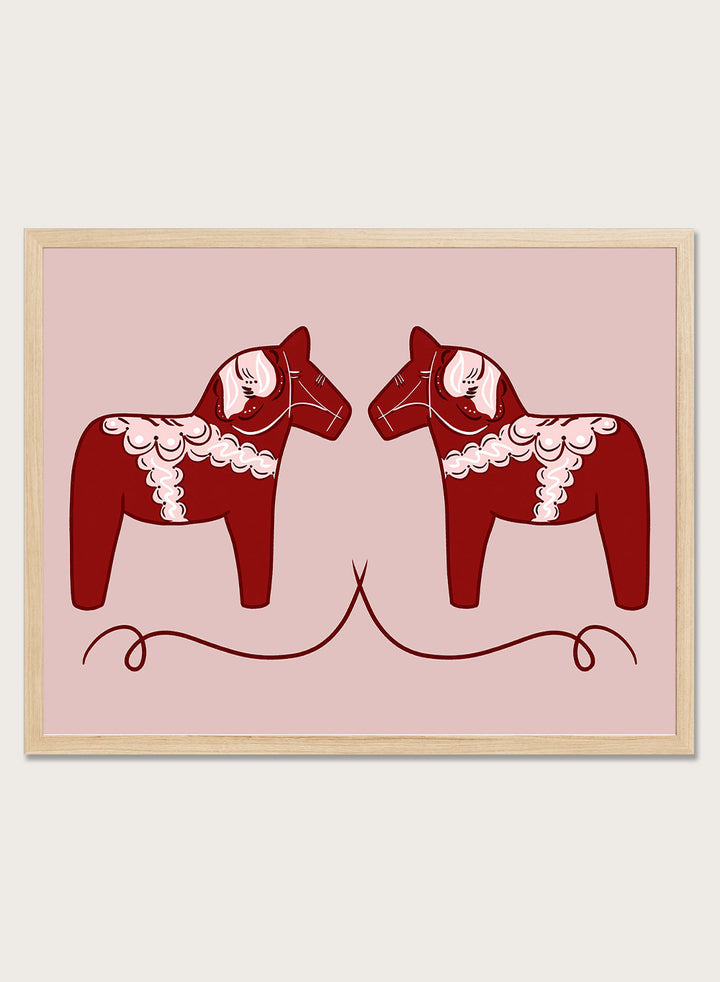Two red Dala horse figures with white patterns on a pink background. Nordic Horses Twins by Athene Fritsch is a Scandinavian folk art illustration art print featuring Swedish Dala horses, bold red color, and modern wall art design.