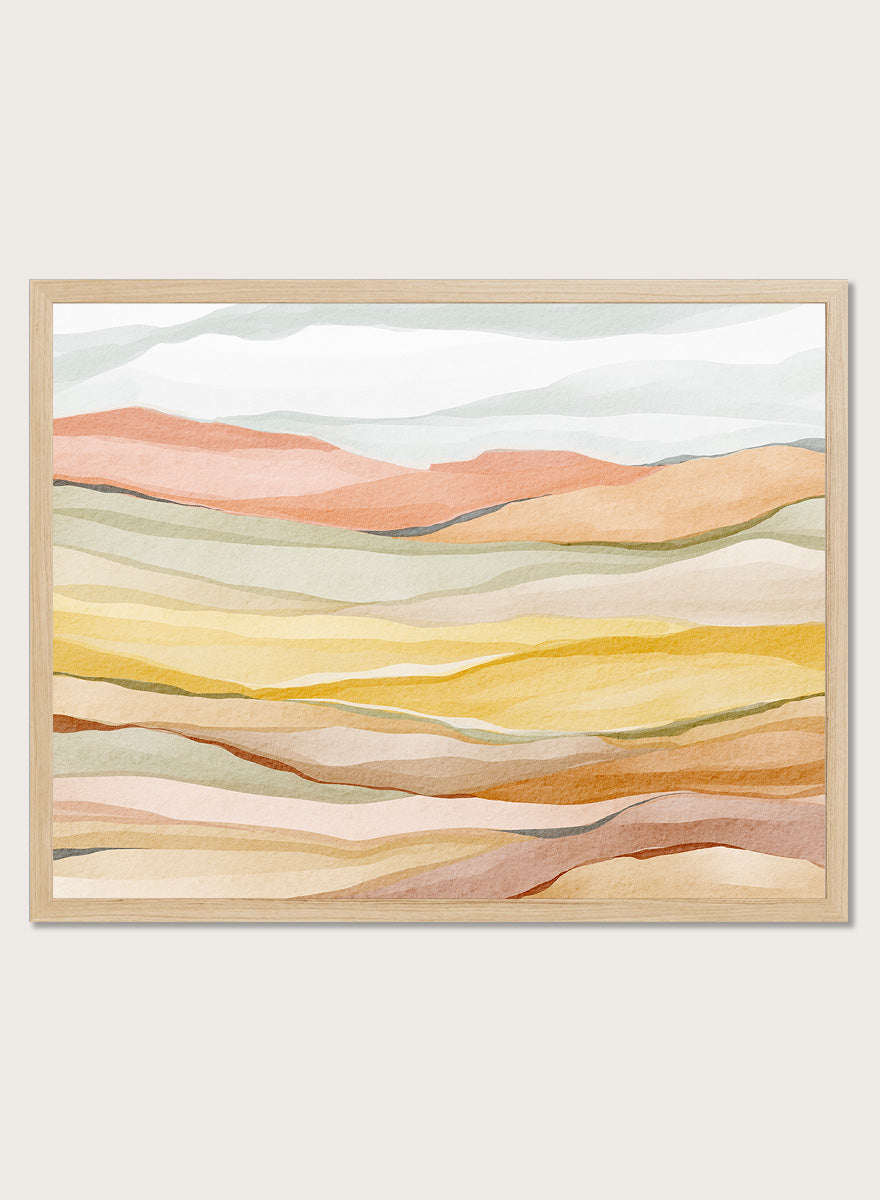 Framed abstract landscape wall art featuring layered wavy hills in soft peach, yellow, beige, and muted green tones. Shop Warm Horizon Layers by Nikita Jariwala, an abstract landscape wall art print poster with layered hills and mountains, soft yellow fields, and warm peach tones.