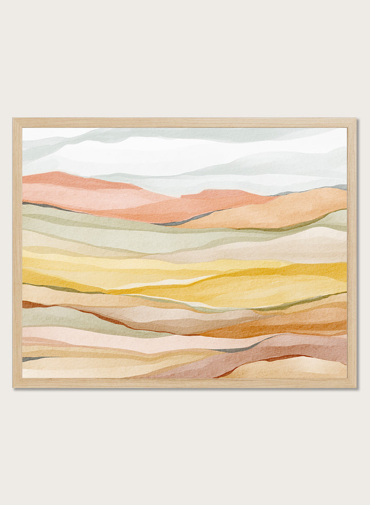 Framed abstract landscape wall art featuring layered wavy hills in soft peach, yellow, beige, and muted green tones. Shop Warm Horizon Layers by Nikita Jariwala, an abstract landscape wall art print poster with layered hills and mountains, soft yellow fields, and warm peach tones.