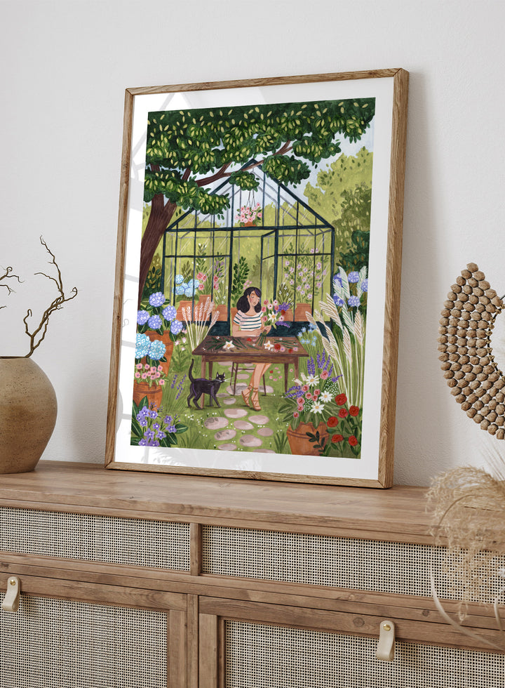 Garden Flower Arranging by Caroline Bonne Müller is a floral garden art print featuring greenhouse, woman arranging flowers, cat illustration, and modern aesthetic botanical scene.