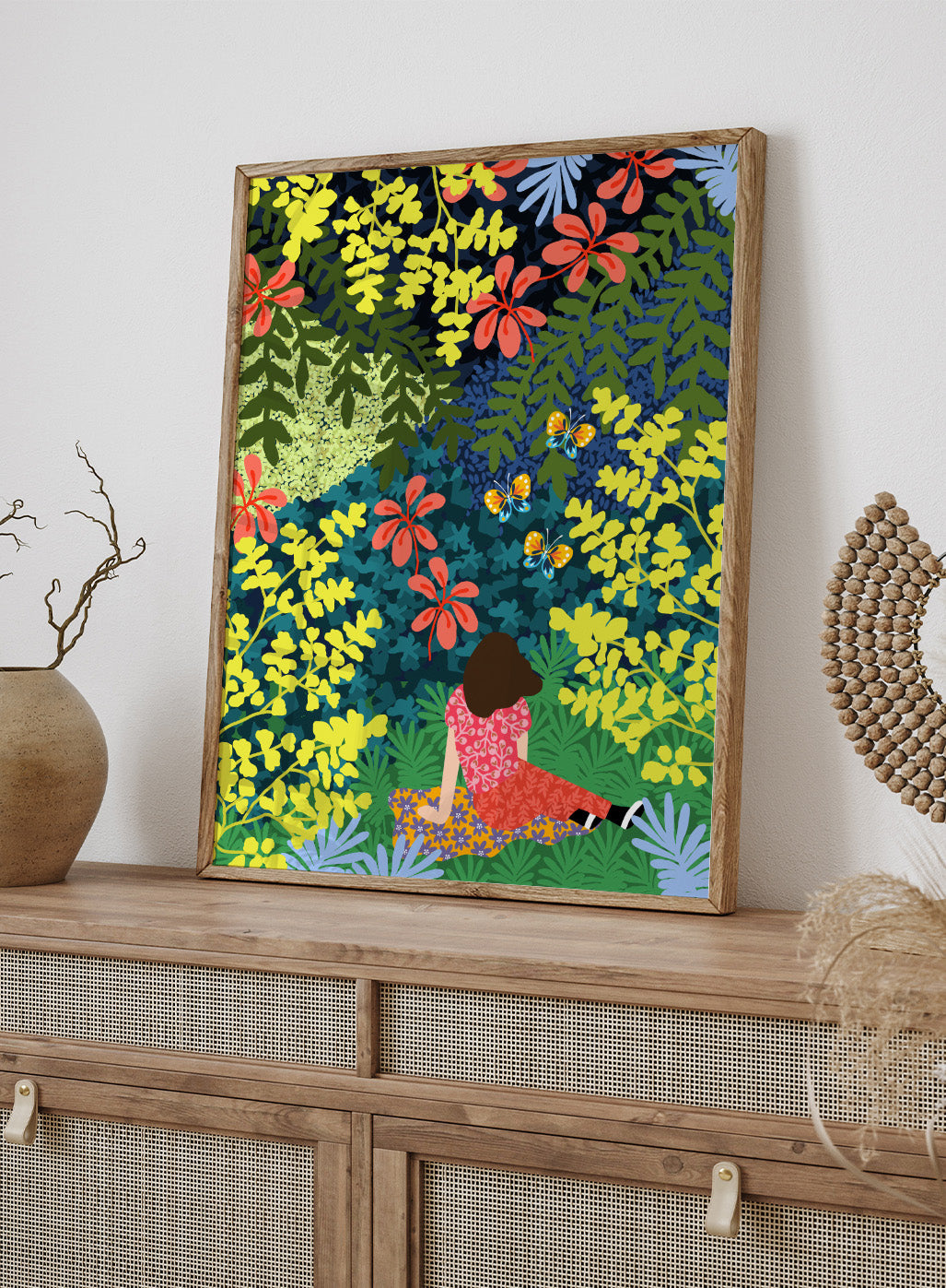 Illustration of a person sitting among colorful flowers and foliage. Picnic in the Forest by Rafaela Mascaro fine art print featuring lush botanical forest, oversized leaves, butterflies, modern colorful wall art poster.