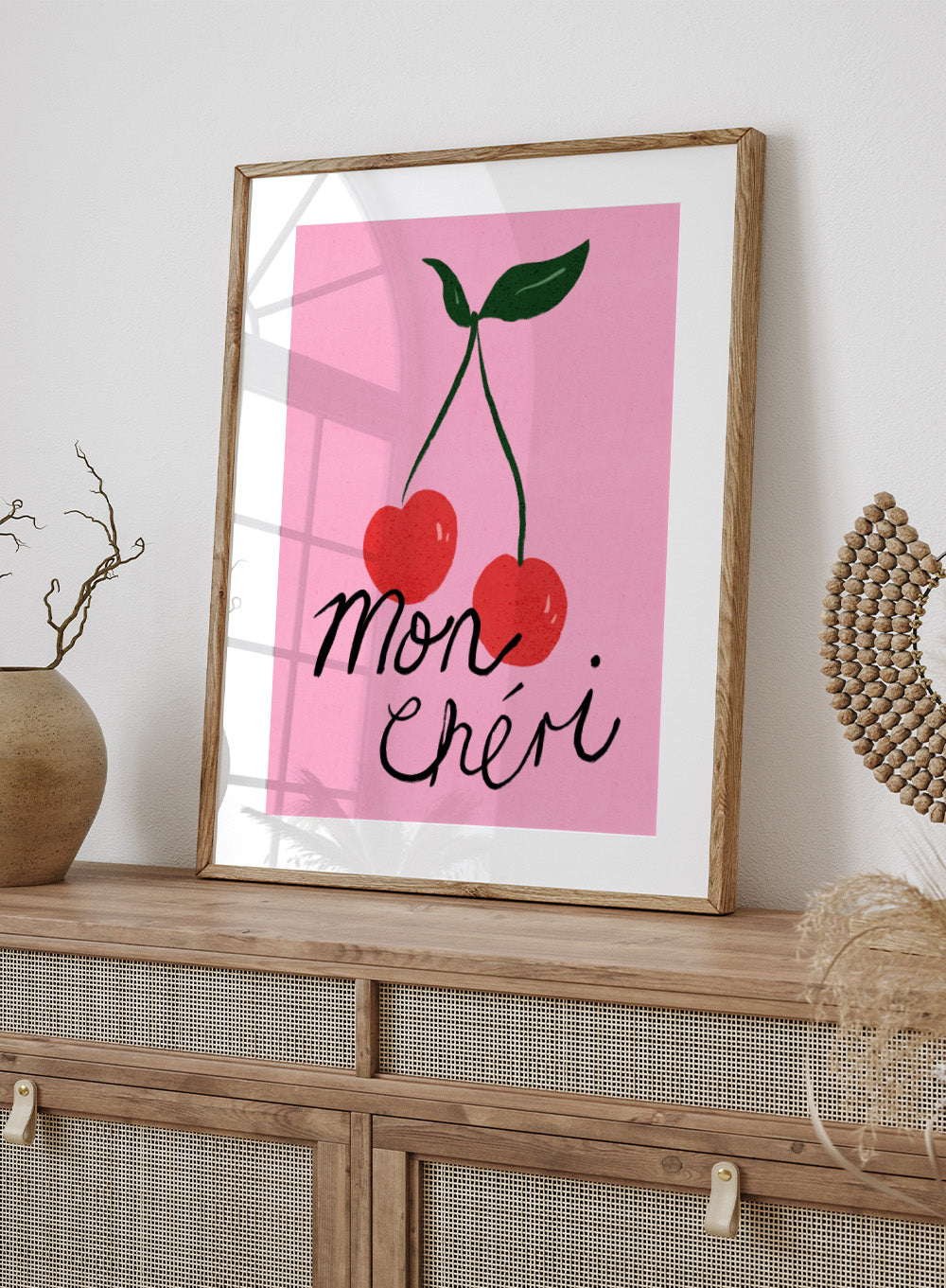 Two red cherries with green stems on a pink background and 'mon chéri' text. Mon Chéri by Dirkie Nell is a cherry typography art print featuring bold red fruit and playful lettering. A colorful love-inspired wall poster.