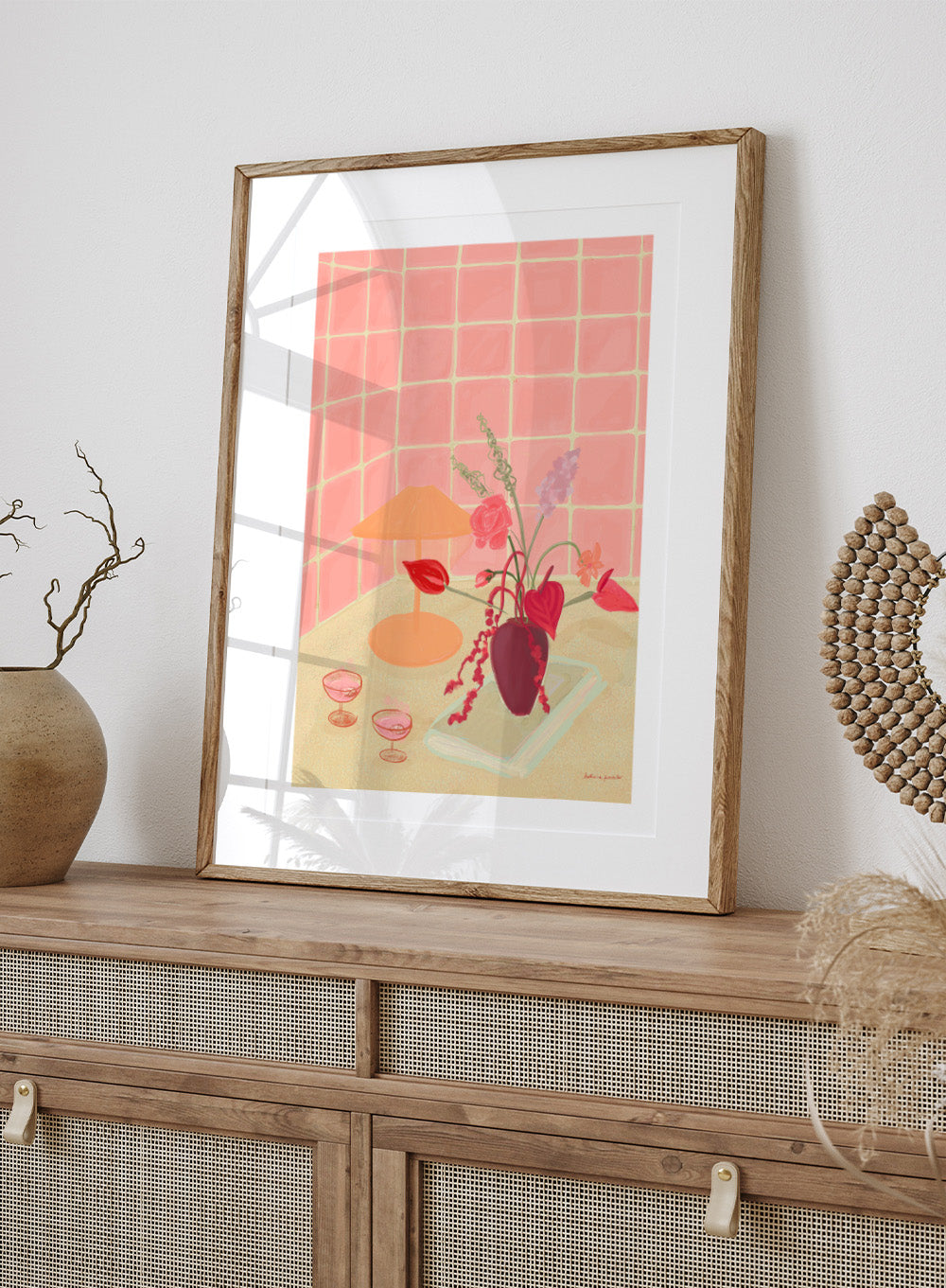 Illustration of a table with a vase of flowers, two glasses, and an orange lamp against a pink tiled wall. Bubbly by Katharina Puritscher art print featuring pink tiled walls, floral still life, coupe glasses, and a cozy tabletop scene. Officially licensed wall poster.