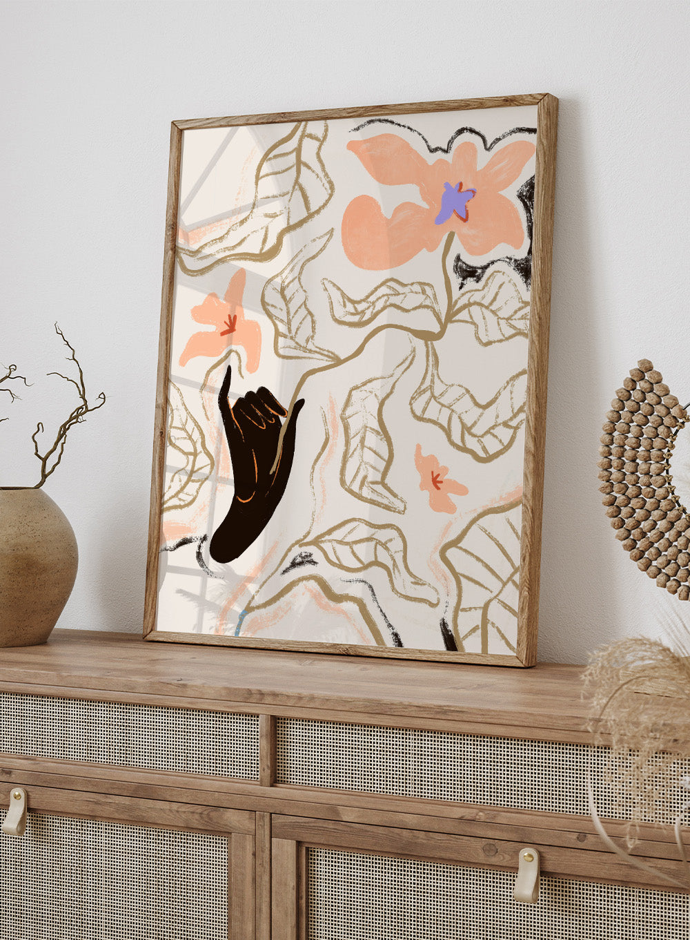 Abstract artwork with a black hand reaching towards flowers on a light background. Fleur by Arty Guava is a modern floral art print with soft abstract flowers and hand-drawn linework. Officially licensed wall poster with framing.