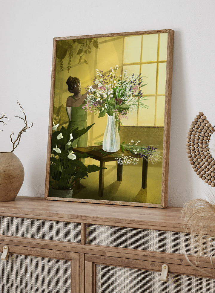 Woman in a green dress holding a bouquet of flowers in a softly lit room. In the Cracks of Light I Dream by Goed Blauw is a floral art print and wall poster featuring a woman arranging flowers in warm window light.