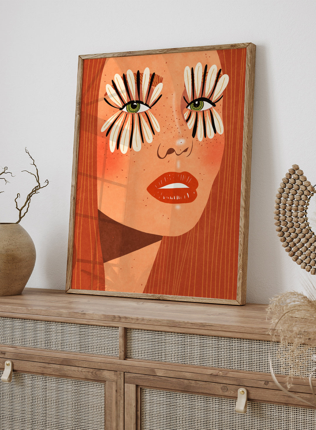 Illustration of a face with flower-like eyes on an orange background. Flower Eyes by Raissa Oltmanns fine art print featuring bold female portrait with floral lashes, modern contemporary wall decor poster.