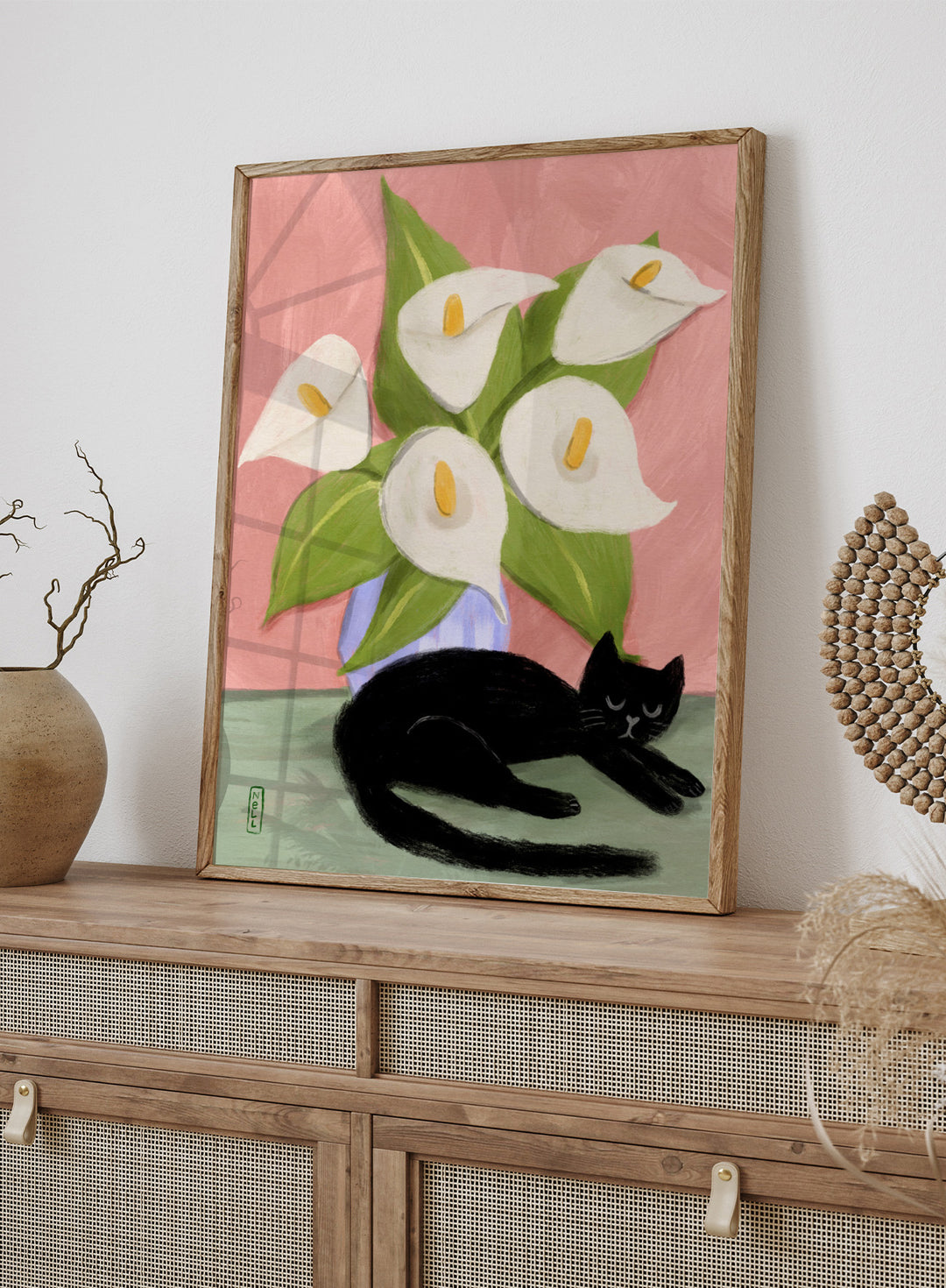 Black cat lying on a surface with white flowers in a blue vase against a pink background. Lilies In a Vase and a Black Cat by Dirkie Nell is a contemporary floral cat art print featuring hand painted lilies, soft pink tones, and playful still life illustration.
