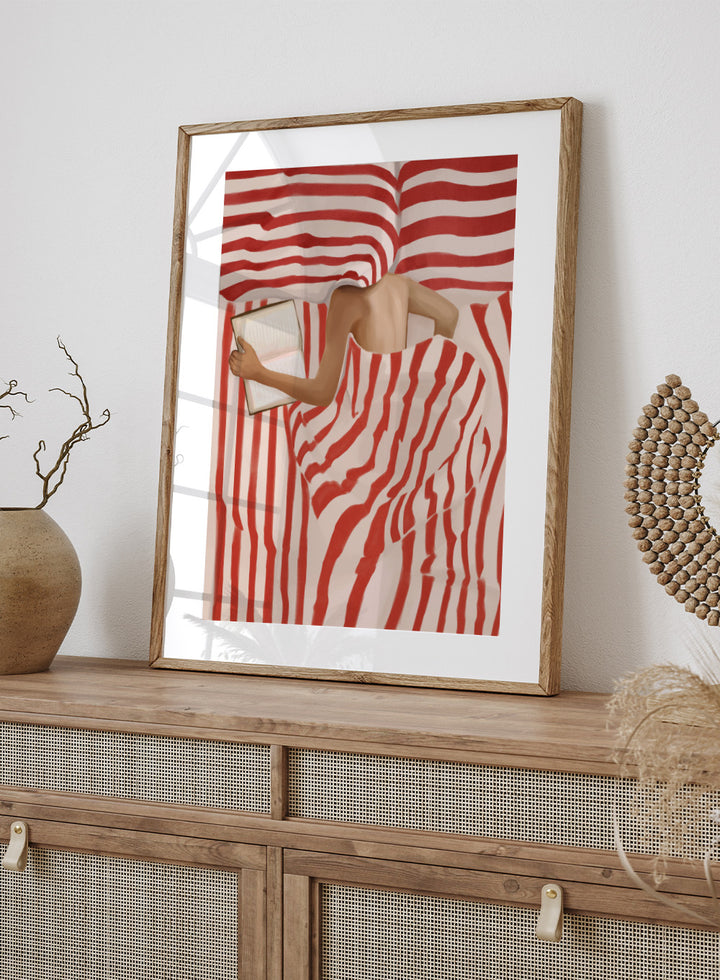 Between the Lines by Flow Line art print shows a woman reading in bed wrapped in red striped bedding. A modern lifestyle wall poster inspired by slow evenings.