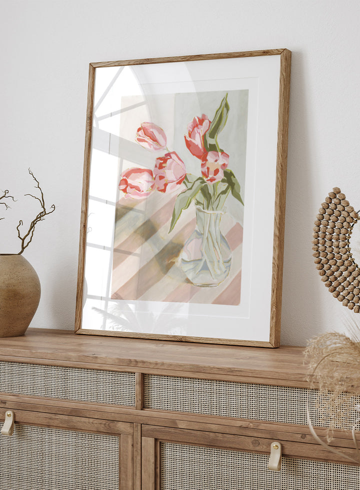 Artistic depiction of pink tulips in a clear vase on a striped background. Tulips in a Vase by Lucrecia Caporale is an officially licensed still life art print featuring pink tulips in a glass vase. Available framed or unframed.