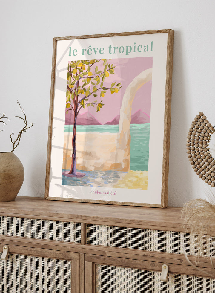 Artistic depiction of a tropical scene with a tree, beach, and mountains, featuring the text 'le rève tropical' and 'couleurs d'été'. Le Rêve Tropical Lemon Tree by Goed Blauw is a coastal art print and wall poster featuring a lemon tree, archway, and ocean view in warm pastel tones.