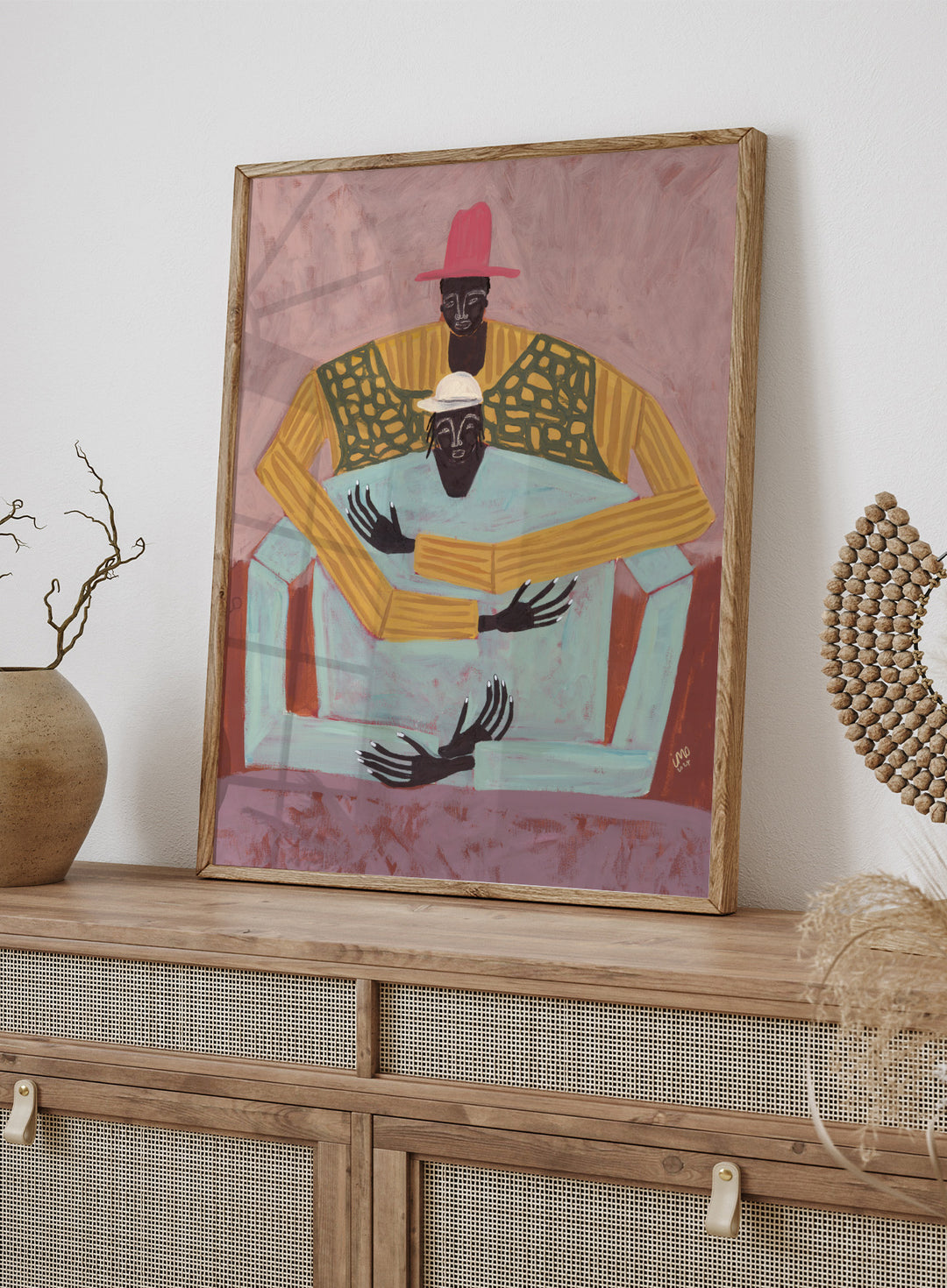 Artistic depiction of two figures sitting together with a pink background. The Hug by Studio IMO (Ibi Meier-Oruitemeka) is a modern figurative art print featuring two figures embracing in a bold contemporary wall poster design.