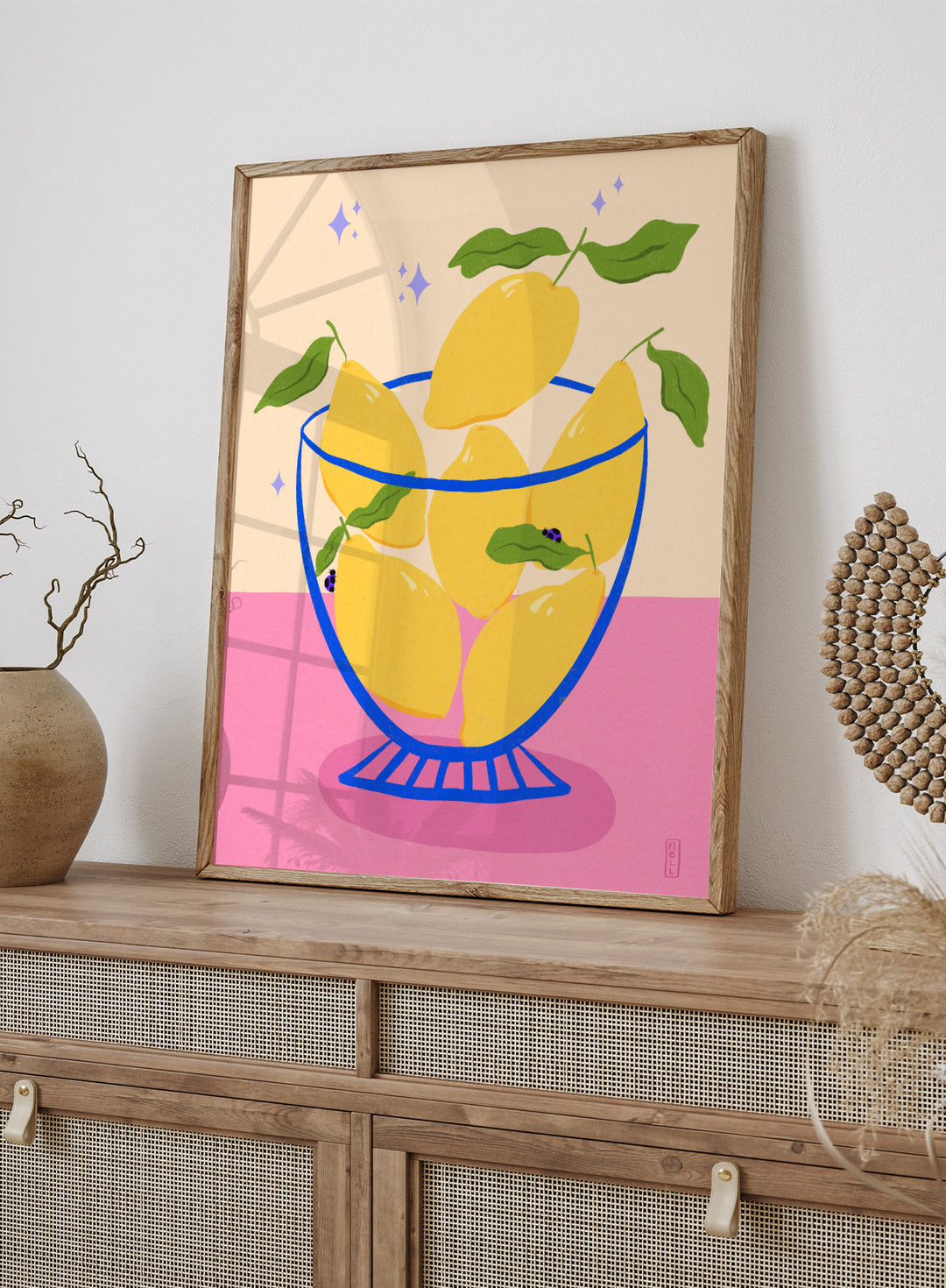 Illustration of lemons in a glass bowl with green leaves on a pink and beige background. Blue Floral Arrangement by Dirkie Nell is a botanical floral art print featuring deep blue flowers, folk inspired illustration, modern wall art, and expressive hand painted details.