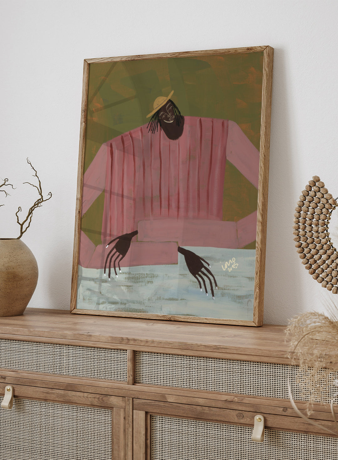 Artistic depiction of a person wearing a pink shirt and straw hat on a textured background. For Now I Don’t Know by Studio IMO (Ibi Meier-Oruitemeka) is a modern figurative art print with a seated figure and contemporary portrait wall poster design.