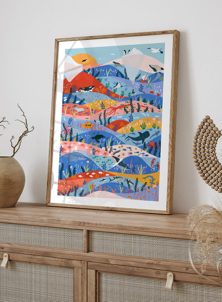 A colorful illustrated art print featuring stylized mountains, sea life, and coastal scenery in layered wavy bands of blue, pink, orange, yellow, and green. Vibrant Ocean Life by Ceyda Alasar ocean art print featuring whales, sharks, rays, turtles, coral reefs, sea plants, and colorful marine life.