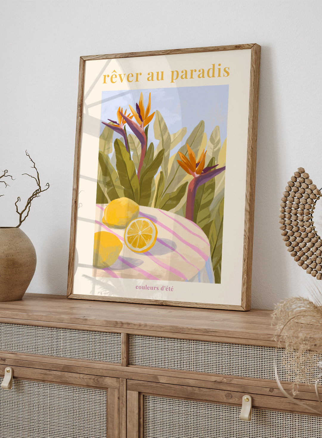 Illustration of tropical flowers and lemons with 'rêver au paradis' text on a light background. Rêver Au Paradis Lemon by Goed Blauw is a summer art print and wall poster featuring lemons, tropical leaves, and bird of paradise flowers in warm, vibrant tones.