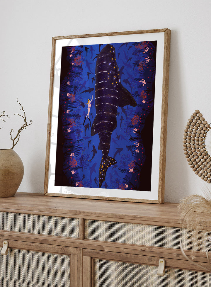 An illustrated art print featuring a large whale shark swimming through a deep blue ocean filled with smaller fish and coral. Diver and Whale Shark art print by Ceyda Alasar features a dramatic underwater view with a whale shark, diver, coral, and rich ocean blues.