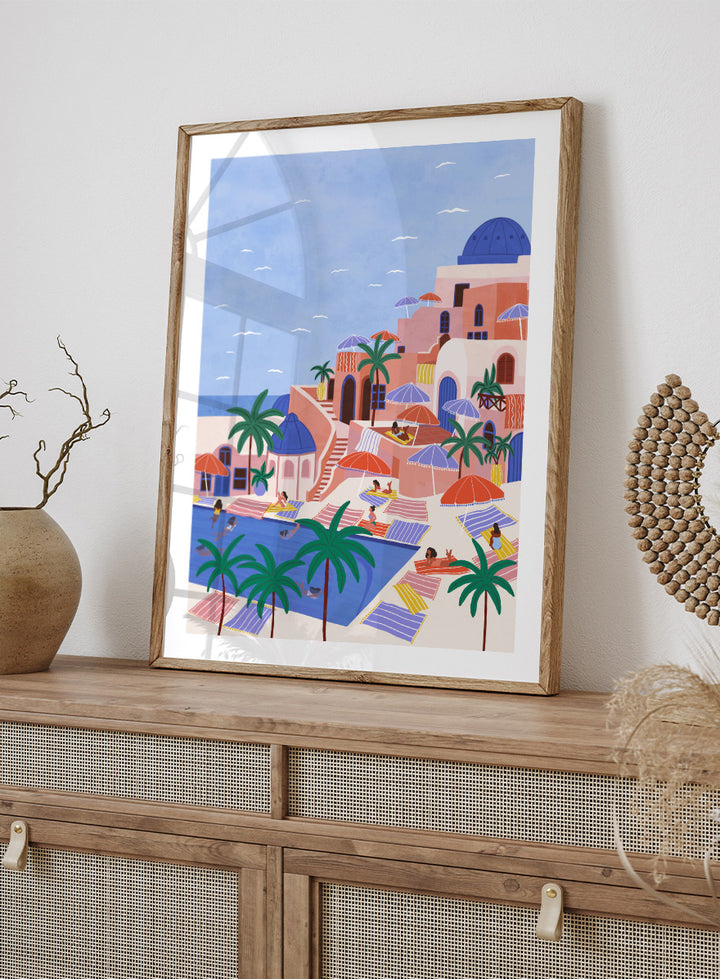 A stylized art print depicting a Mediterranean resort scene with palm trees, beach umbrellas, lounge chairs, a swimming pool, and pastel-colored buildings under a light blue sky. Mediterranean Poolside Retreat by Ceyda Alasar travel art print featuring a colorful coastal resort, palm trees, sunbathers, striped umbrellas, and sea views.