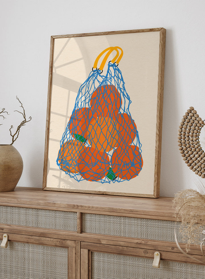 Blue mesh bag filled with orange fruits on a beige background. Oranges In a Net Bag by Rosi Feist is a modern minimalist fruit art print with bold color and Bauhaus-inspired graphic design. Officially licensed fine art poster with framing.