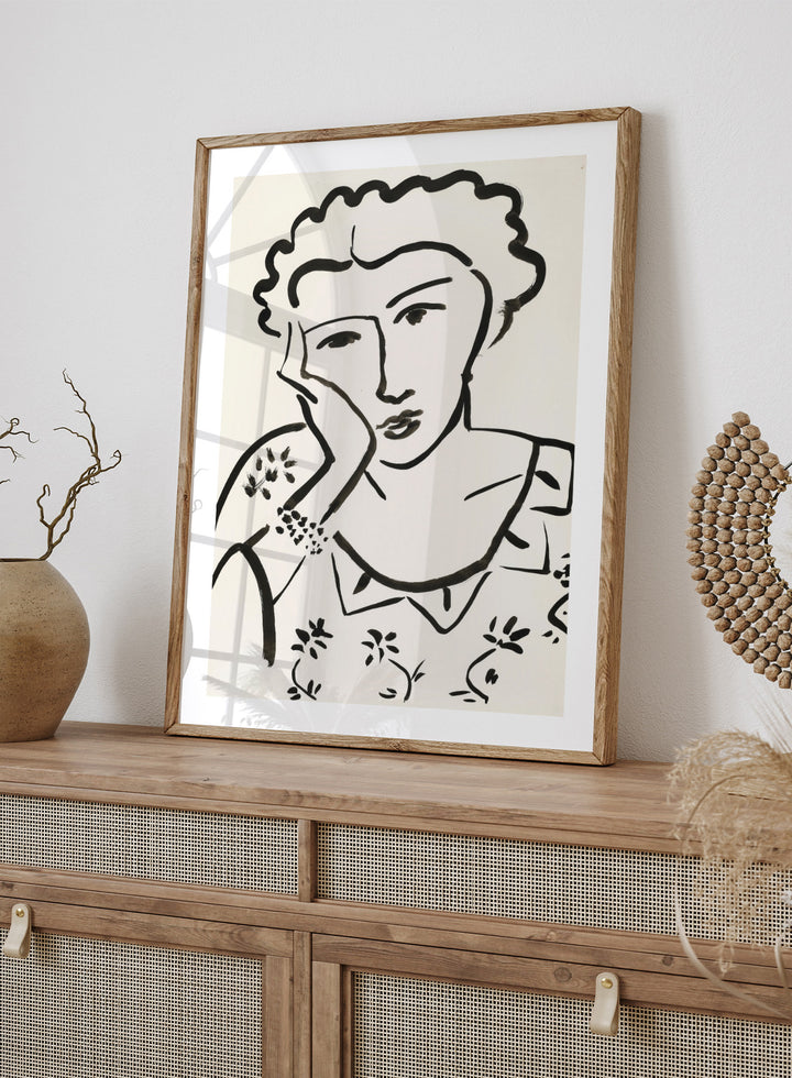 Black line art of a woman with floral patterns on a white background. Jeune Fille Accoudée by Henri Matisse is a minimalist portrait art print featuring expressive black linework, floral detailing, and refined French modernist design.