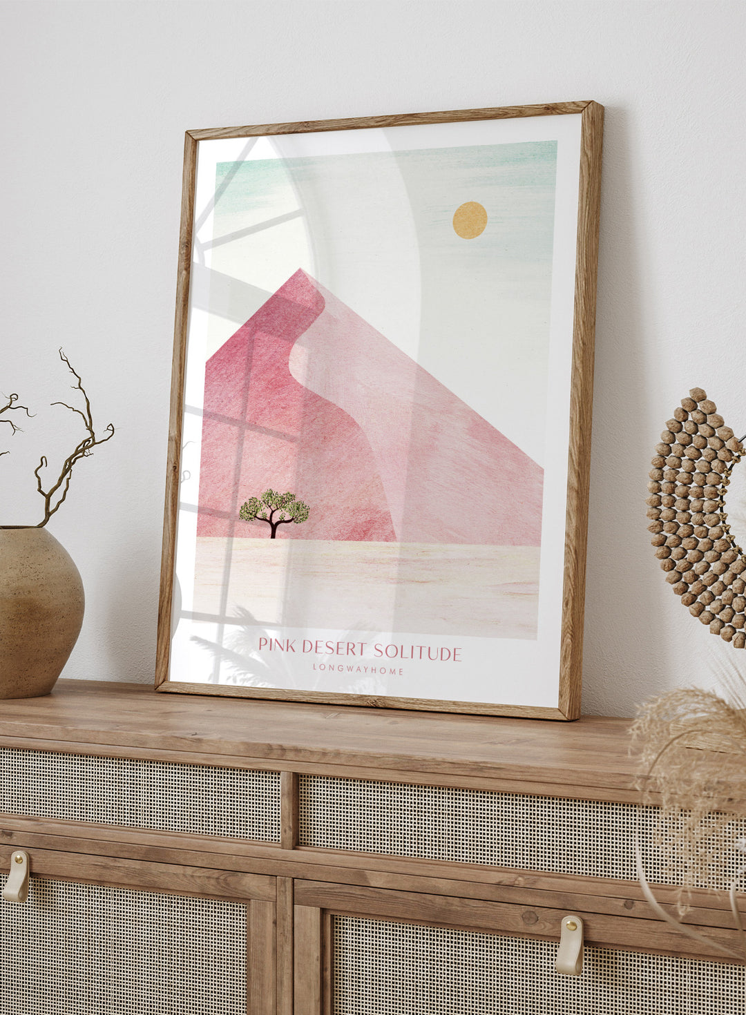 Artistic depiction of a pink desert with a solitary tree and a yellow sun. Pink Desert Solitude by Longwayhome is a minimalist desert art print featuring soft pink dunes, abstract landscape scenery, and calming modern design.