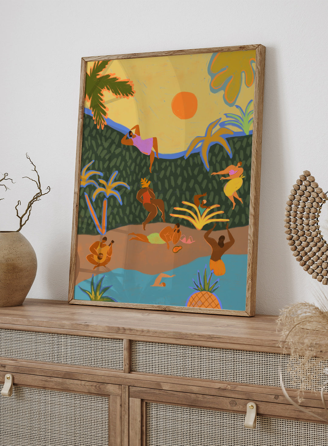 A colorful tropical beach illustration featuring stylized figures relaxing on a sandy shore, swimming in blue water, lounging under palm trees, with a yellow sky and orange sun. Summer Paradise by Arty Guava premium framed fine art print featuring women swimming, dancing, and relaxing in a vibrant tropical landscape.
