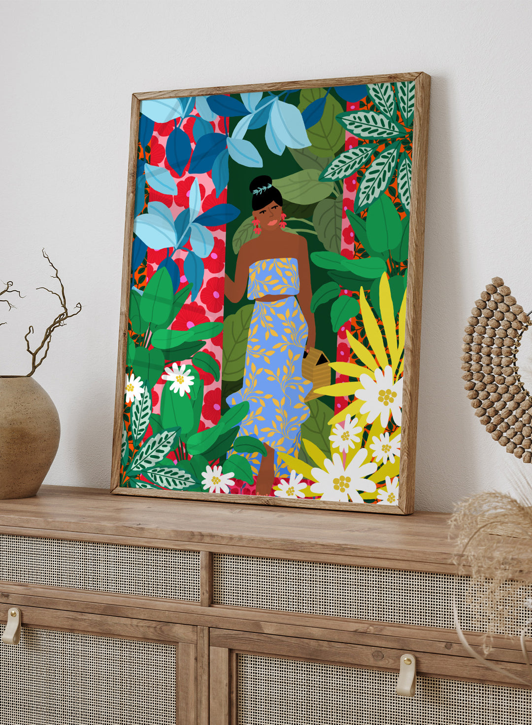 Woman in a blue dress surrounded by colorful foliage and flowers. Woman In A Dress With Flowers by Rafaela Mascaro is a vibrant botanical art print featuring lush foliage, colorful florals, decorative patterns, and tropical charm.