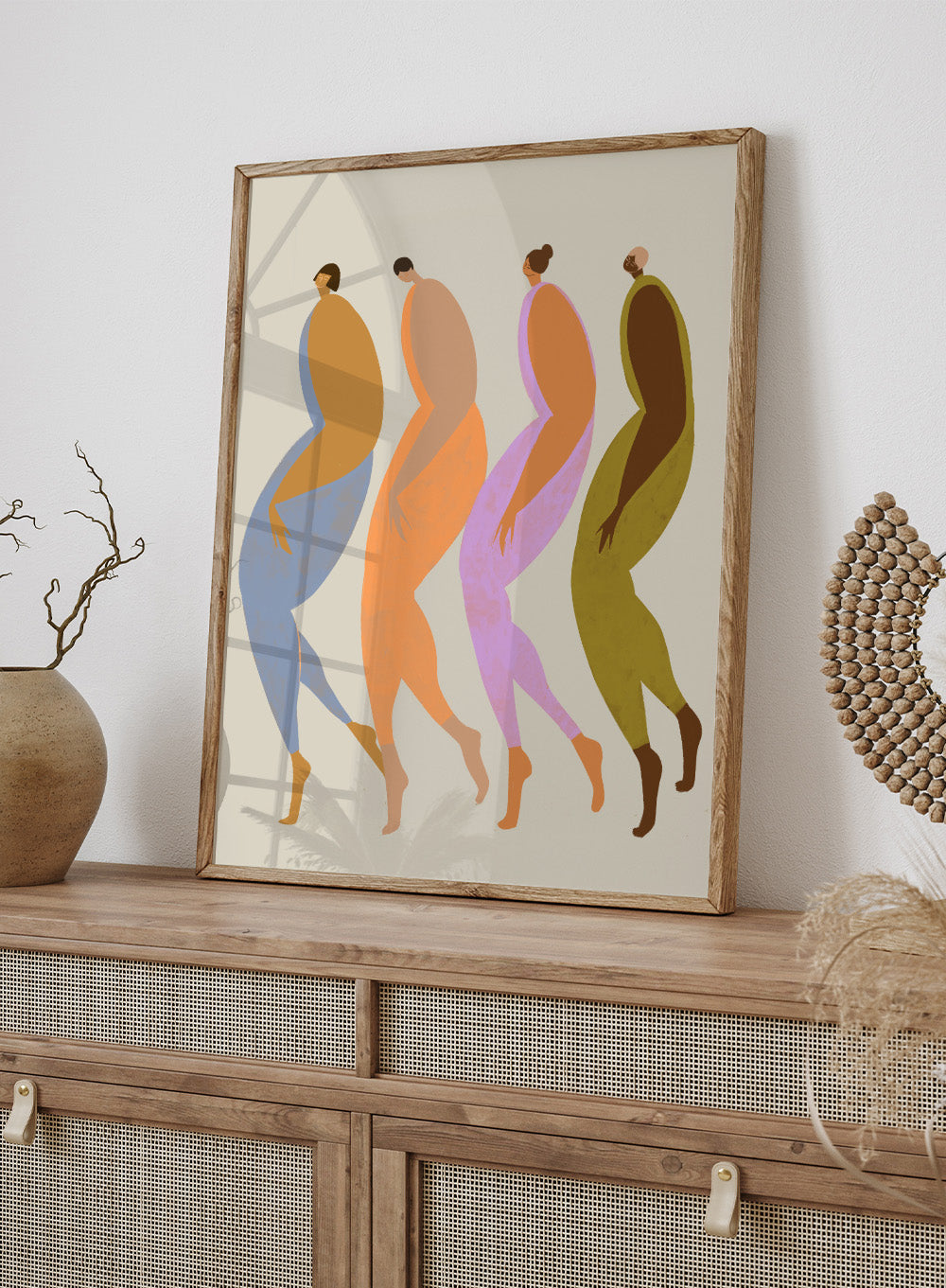 Abstract illustration of four stylized figures in various colors on a beige background. We The Giants by Arty Guava is a modern art print of four bold figures walking together, celebrating strength and sisterhood. Officially licensed wall poster.