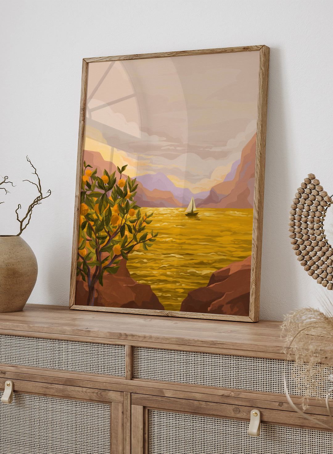 Sailing boat on a yellow sea with mountains and lemon tree in the foreground. Golden Sunset by Goed Blauw is a coastal art print and wall poster featuring a sailboat on a glowing ocean with cliffs and an orange tree.