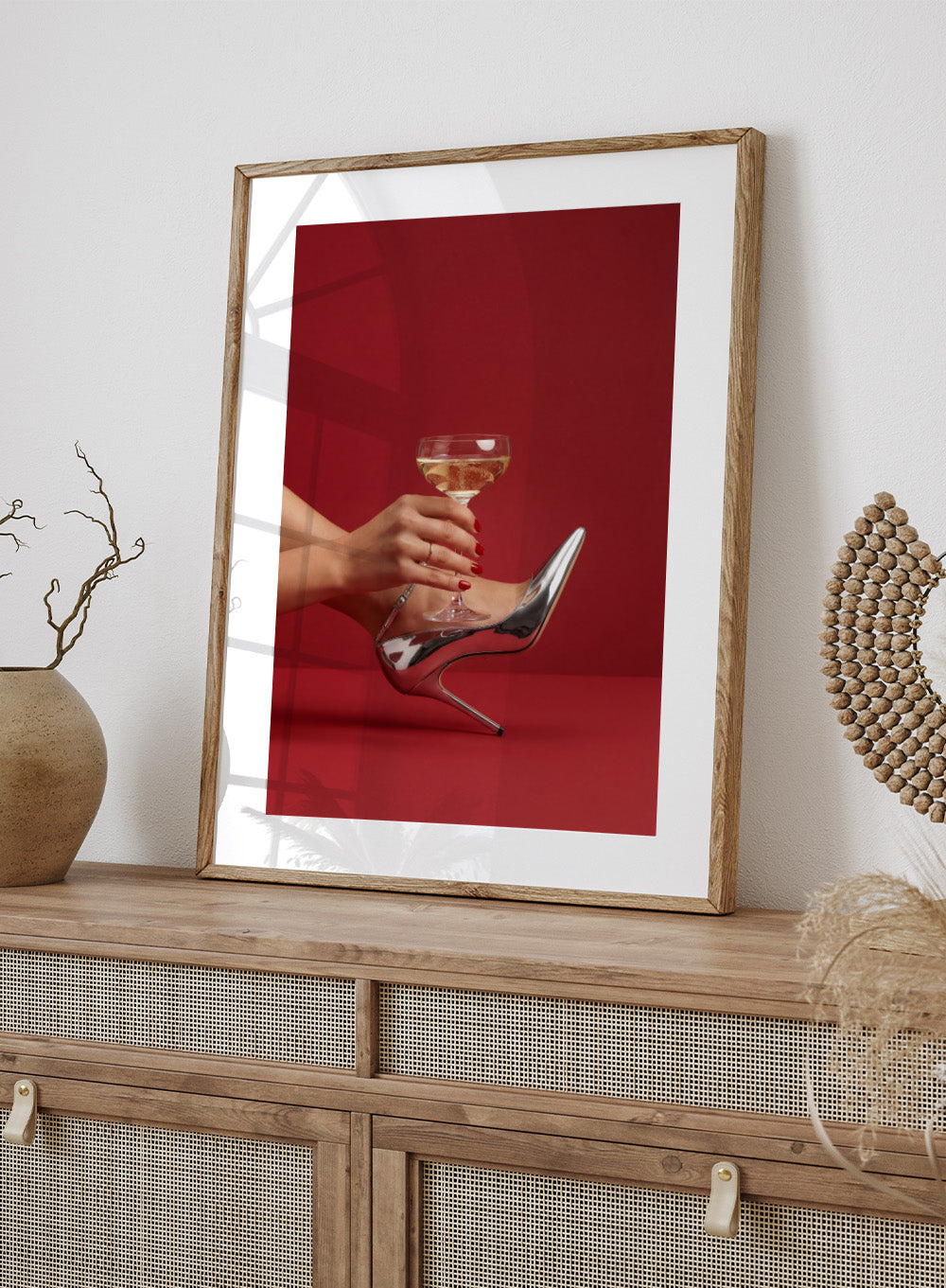 High-heeled shoe holding a glass of white wine against a red background, High Heels and Champagne by Andreas Magnusson is a fashion illustration art print featuring high heels, champagne glass imagery, bold red tones, and modern contemporary wall art style.