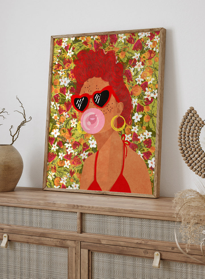 Illustration of a woman with red hair, sunglasses, and a pink bubble gum against a floral background. Strawberry Lady by Raissa Oltmanns fine art print featuring bold female portrait with strawberry background, modern colorful wall decor poster.