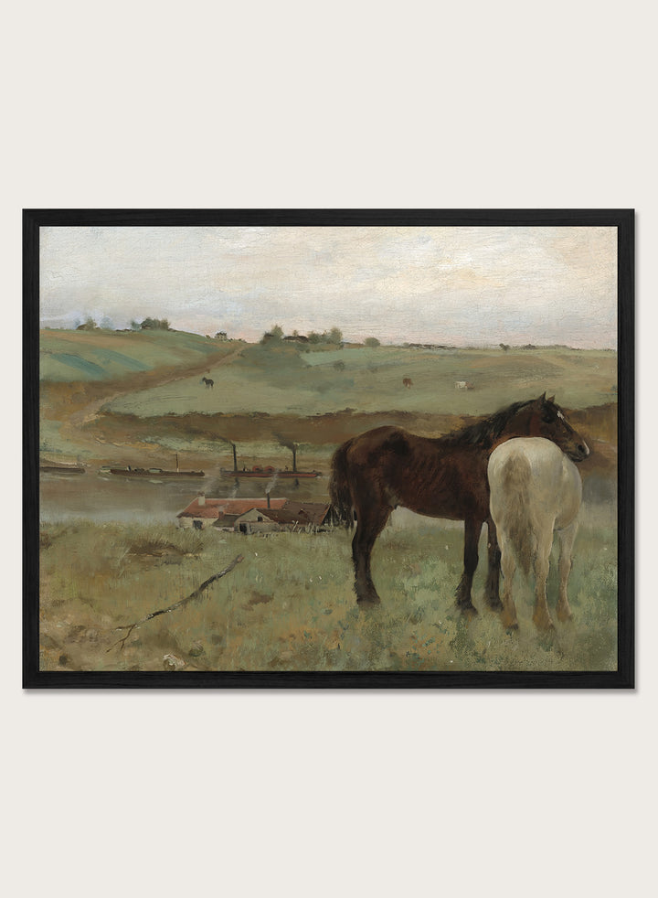 A framed landscape painting depicting two horses in a grassy field, with a muted sky and distant hills. Horses in a Meadow by Edgar Degas is a vintage horse art print featuring two horses standing together in a green field with a river, hills, and distant village.