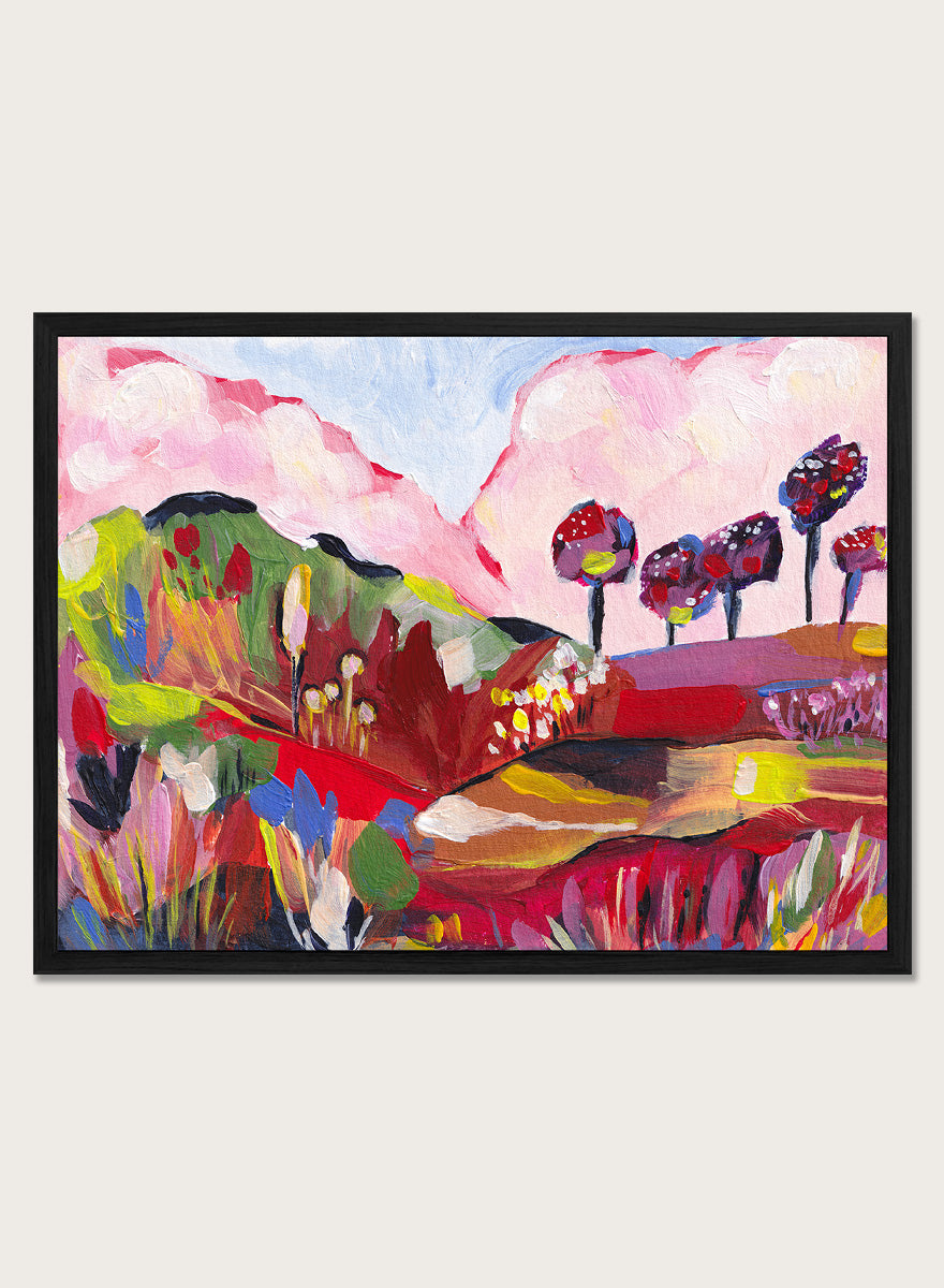 A framed abstract landscape painting featuring pink clouds, green hills, and colorful stylized trees. Shop Vibrant Fantasy Landscape by Dirkie Nell, a colorful landscape art print featuring pink clouds, rolling hills, wildflowers, and bold abstract color.