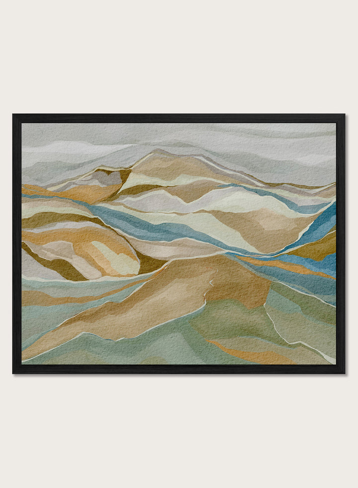 Framed abstract landscape wall art featuring layered hills and winding blue river-like lines in beige, tan, muted green, and blue tones, shown against a light neutral background. Shop Abstract Mountain Serenity by Nikita Jariwala, a modern mountain wall art print featuring layered abstract hills, earthy tones, and soft blue and sage accents.