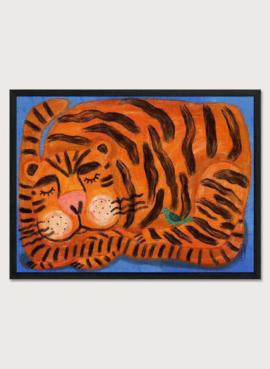 A framed painting of a sleeping tiger on a blue background. The tiger is orange with bold black stripes, has a pink nose and cheeks, and a small green bird near its side. A framed painting of a sleeping tiger on a blue background. The tiger is orange with bold black stripes, has a pink nose and cheeks, and a small green bird near its side. 
