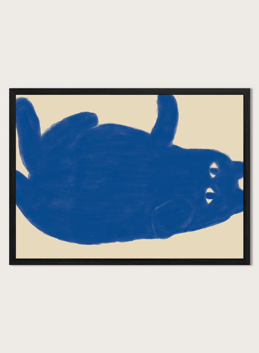 A framed art print featuring a bold blue abstract cat illustration on a warm beige background. Whimsical Blue Cat by The Art Concept is a playful cat art print featuring a lounging blue cat on a warm cream background in a bold minimalist style.