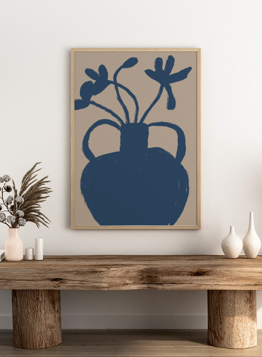 A minimalist art print featuring a dark blue silhouette of a vase with two handles and abstract flower stems, set against a warm beige background. Minimalist Blue Blooms by The Art Concept is a modern floral art print featuring a deep blue vase, loose flowers, and a warm beige background.