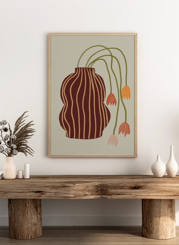 A stylized botanical art print featuring a dark brown vase with vertical gold stripes and several trailing flowers in orange, pink, and olive green on a warm beige background. Striped Vase Drooping Flowers by The Art Concept art print featuring a burgundy striped vase and soft drooping blooms in warm earthy tones.