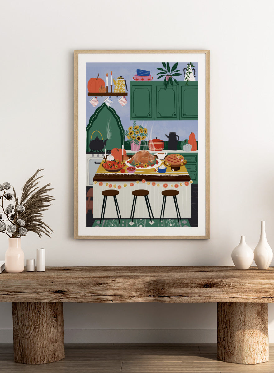 A framed art print depicting a cozy, stylized autumn kitchen scene with a large roasted turkey on a table covered in fall dishes, green cabinets, pumpkins, and three bar stools. Cozy Thanksgiving Kitchen by Ceyda Alasar kitchen art print featuring a turkey feast, pie, pumpkins, flowers, candles, and warm autumn decor.