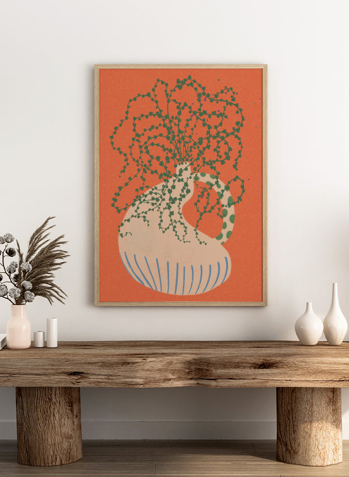 Shop Green Trailing Plant by Nikita Jariwala, a botanical wall art print poster featuring a trailing houseplant, cream vase, coral background, and bold green tones.
