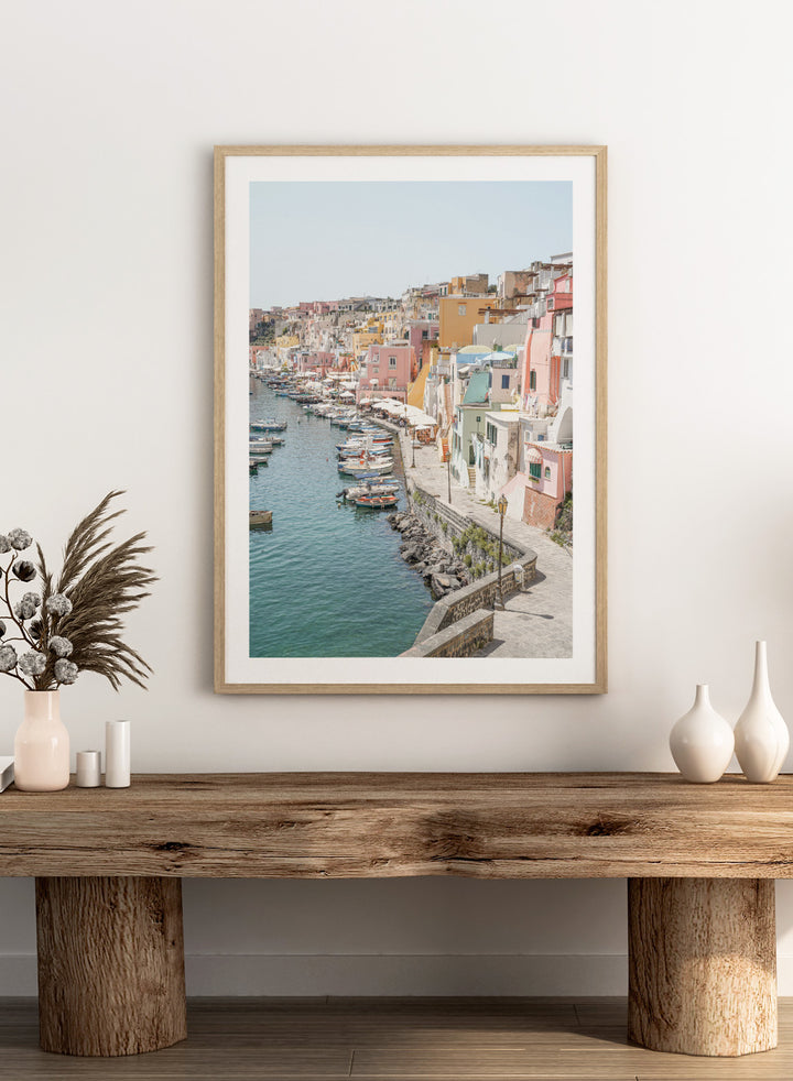 Colorful coastal town with boats docked along a waterfront. Colorful Italian Harbor by Henrike Schenk is a coastal photography print featuring pastel waterfront architecture, fishing boats, turquoise waters, and Mediterranean charm.