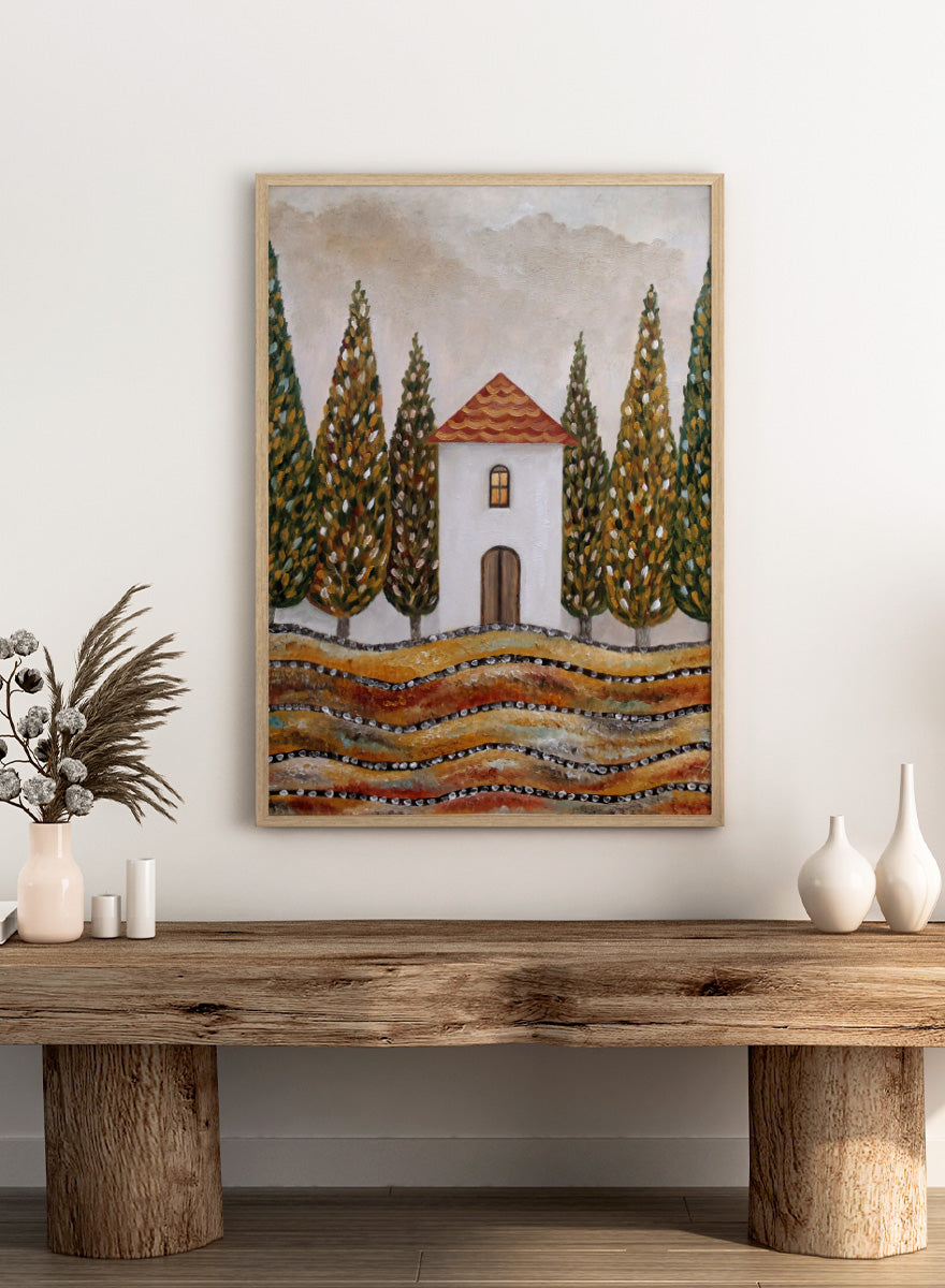A stylized landscape painting of a small white house with a red-orange tiled roof, surrounded by tall green and gold trees, with wavy golden fields in the foreground. Shop Tuscan Cypress House by Angeles M. Pomata, an autumn landscape art print featuring a white country house, tall cypress trees, terracotta roof, and warm earthy tones.